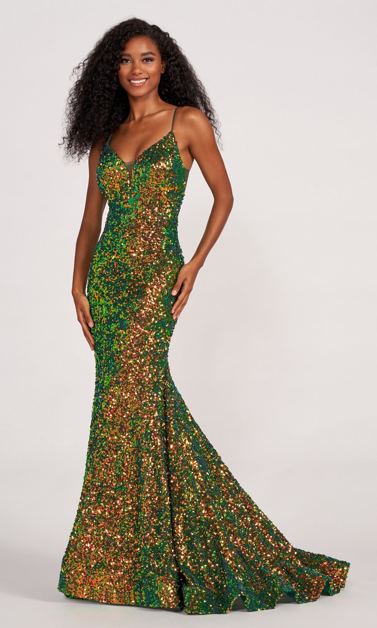 A woman models the Ellie Wilde Long Stretch-Sequin Prom Dress, a floor-length sleeveless gown in green and gold, standing against a plain background.